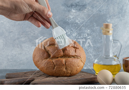Man covering his rye bread with oil 72880635