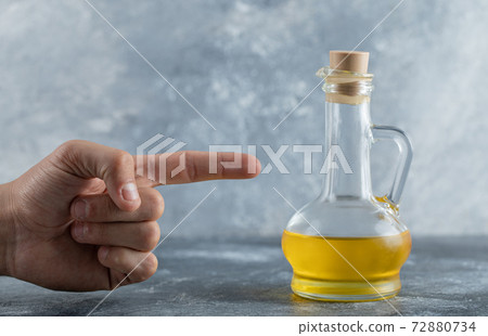 Man point finger to bottle of oil Man point finger to bottle of oil 72880734