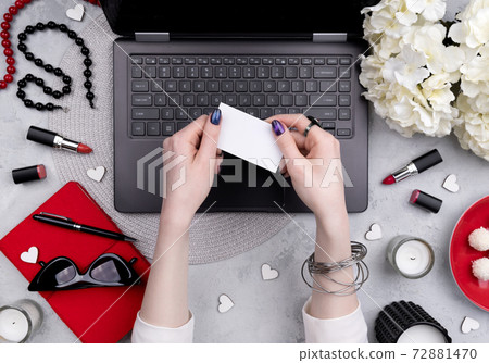 Beautiful groomed woman's hands holding business greeting card on the home office table 72881470