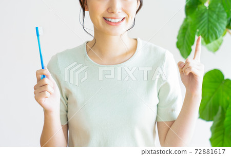 Young woman pointing while brushing her toothbrush Young woman pointing while brushing her toothbrush 72881617
