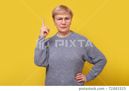 Senior woman pointing up looking angry, indicating direction with fingers, giving advice. 72883325