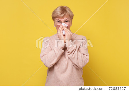 Portrait of an attractive woman sneezing while standing against a white background Portrait of an attractive woman sneezing while standing against a white background 72883327