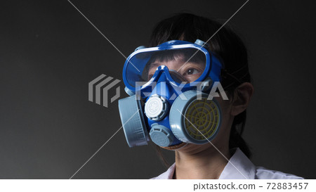 Asian woman doctor in a chemical protective medical mask and protective goggles. Doctor uniform clothing and half mask replaceable particulate filter respirator. Women scientist safety mask 72883457