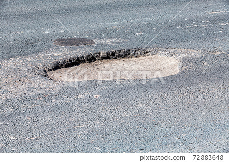 Large pothole an example of poor road maintenance 72883648