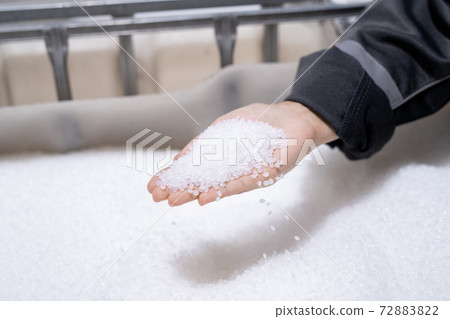 Hand of female worker of polymer processing factory with pile of plastic pellets Hand of female worker of polymer processing factory with pile of plastic pellets 72883822