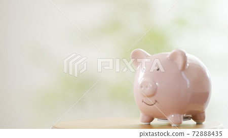 A woman's hand putting coins in a piggy bank 72888435