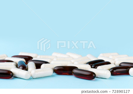 Pharmaceutical pills and vitamins. Medicine or supplement capsules on blue surface. Probiotic, inulin, glucosamine pile. 72890127
