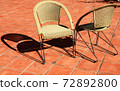 Two wicker chairs with shadows in the sunlight. 72892800