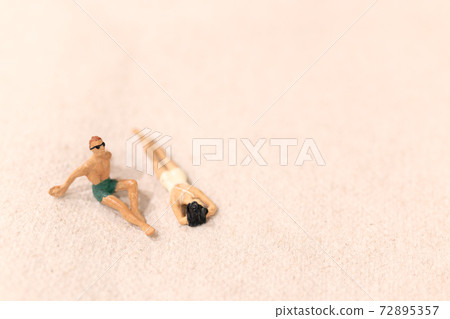 Miniature people , Couple sunbathing together on The beach 72895357