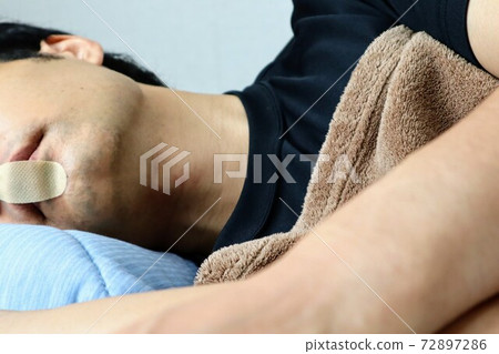 Close-up of a person sleeping with mouse tape 72897286