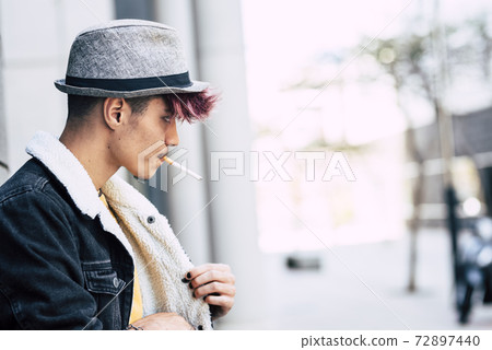 Handsome portrait of young boy hispanic diversitiy man with a cigarette ready to smoke outdoor in the city Handsome portrait of young boy hispanic diversitiy man with a cigarette ready to smoke outdoor in the city 72897440