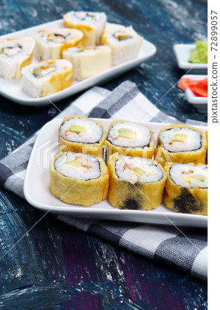 baked sushi rolls with wasabi and ginger on a black background. Japanese oriental cuisine. 72899057