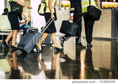 Aircraft team crew boarding scene with captain and hostess assistent fly with luggages reflecting on the floor at the airport gate 72899309
