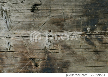 A wooden background. A rusty nail hammered in the center. 72899531