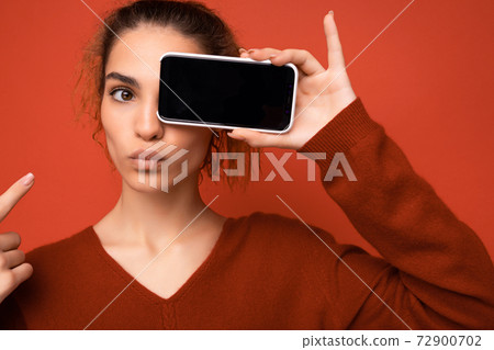 Closeup photo of happy funny young woman wearing dark red sweater isolated over red background Closeup photo of happy funny young woman wearing dark red sweater isolated over red background 72900702