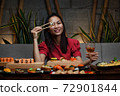 Woman is holding chopsticks with sushi opposite her eye 72901844