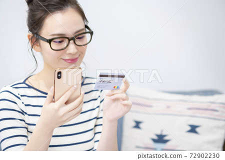 Young woman with smartphone and card 72902230