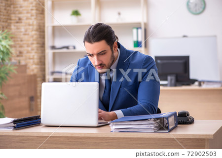 Young male businessman employee working in the office Young male businessman employee working in the office 72902503