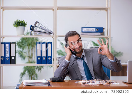 Young male sick employee suffering at workplace 72902505