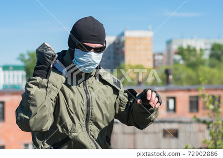 A man wearing a mask and glasses brandishes a knife in the street A man wearing a mask and glasses brandishes a knife in the street 72902886