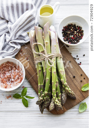 Bunch of raw asparagus stems with different spices 72904929