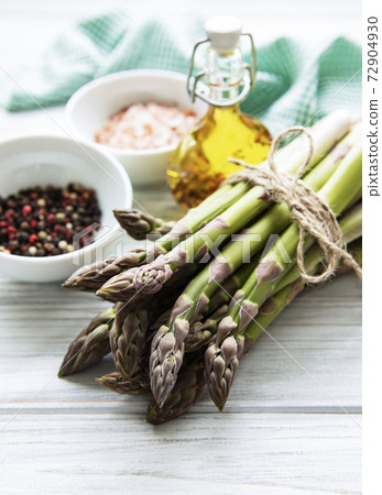Bunch of raw asparagus stems with different spices 72904930