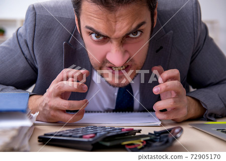 Young male employee unhappy with excessive work in the office 72905170