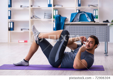 Young handsome employee doing sport exercises in the office Young handsome employee doing sport exercises in the office 72906304