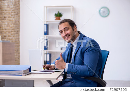 Young male employee working at workplace Young male employee working at workplace 72907303