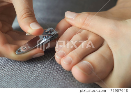 Woman is cutting her nails on toes using nippers by herself, closeup view. 72907648