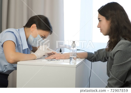 Woman manicurist master is removing cuticle and pterygium using pusher. 72907859