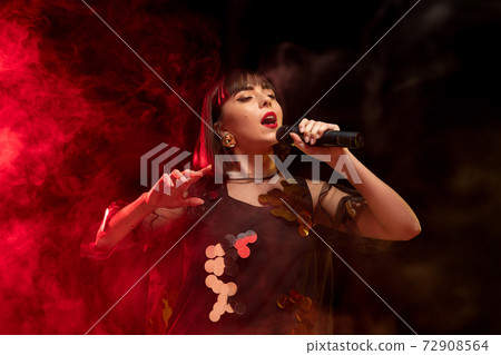 Caucasian female singer portrait isolated on dark studio background in neon light 72908564
