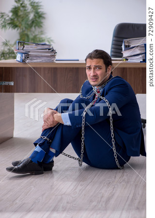 Chained male employee unhappy with excessive work in the office Chained male employee unhappy with excessive work in the office 72909427