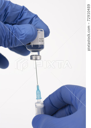 Close up human fingers in gloves, holding covid-19 vaccine vial and syringe with needle. Medical concept. Close up human fingers in gloves, holding covid-19 vaccine vial and syringe with needle. Medical concept. 72910489