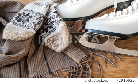 Winter flatlay with white skates for figure skating, a warm scarf and mittens Winter flatlay with white skates for figure skating, a warm scarf and mittens 72910622