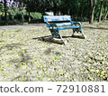 A old green bench ,It has tilted legs and faded color 72910881