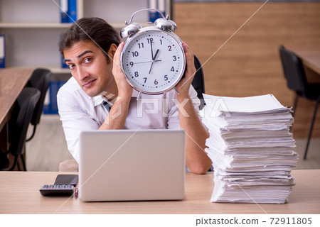 Young male employee in time management concept in the office Young male employee in time management concept in the office 72911805
