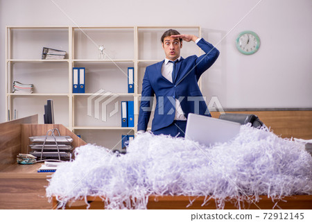 Young male employee and a lot of cut papers in the office 72912145