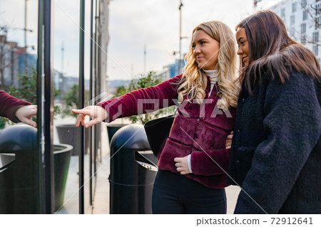 Two Friends Doing Window Shopping In City Two Friends Doing Window Shopping In City 72912641