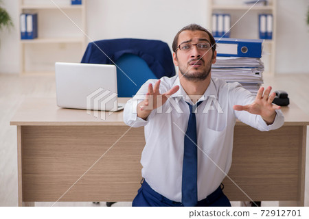 Young businessman unhappy with excessive work in the office 72912701