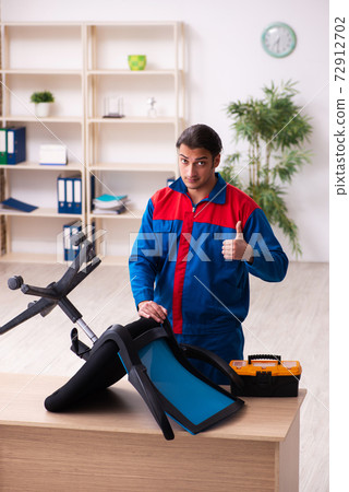 Young male contractor repairing furniture in the office 72912702