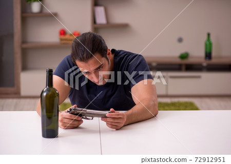 Young male alcoholic committing suicide at home Young male alcoholic committing suicide at home 72912951