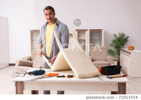 Young male carpenter repairing furniture at home Young male carpenter repairing furniture at home 72913554