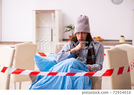 Young sick man suffering at home in pandemic concept 72914018