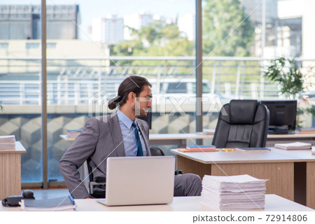 Young male employee in wheel-chair working in the office 72914806