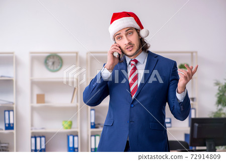 Young male employee working in the office at Christmas Eve Young male employee working in the office at Christmas Eve 72914809