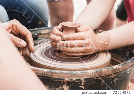 A close up view on ceramic production process on potter's wheel with children. Clay crafts with kids concept A close up view on ceramic production process on potter's wheel with children. Clay crafts with kids concept 72914971