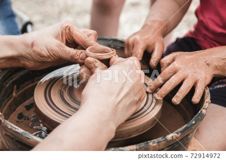 A close up view on ceramic production process on potter's wheel with children. Clay crafts with kids concept A close up view on ceramic production process on potter's wheel with children. Clay crafts with kids concept 72914972