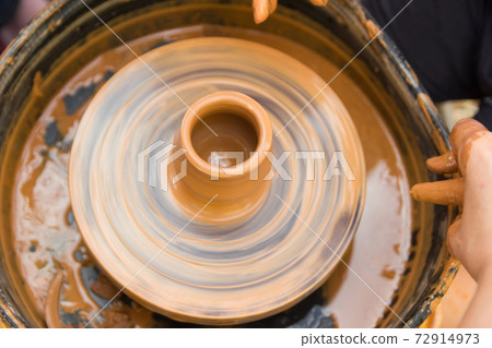 A close up view on ceramic production process on potter's wheel with children. Clay crafts with kids concept 72914973