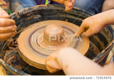 A close up view on ceramic production process on potter's wheel with children. Clay crafts with kids concept 72914978